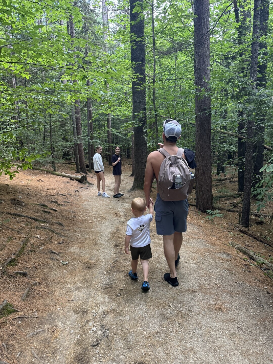 Dakota hiking with his son Dawson, walking toward daughters Bella and Allison on a forest trail